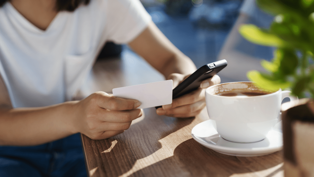 Persona usando una tarjeta NFC con su móvil en una cafetería